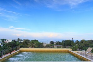 Une piscine située sur le toit, offrant une vue sur la mer et les bâtiments environnants.