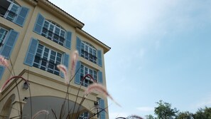 A multi-story building with blue shutters, balconies, and a clear sky. - De Pastel Hotel (Hua Hin)