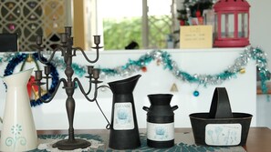 Une table sur laquelle se trouvent un pichet blanc, un chandelier noir, un autre pichet noir et un pot noir avec une étiquette.