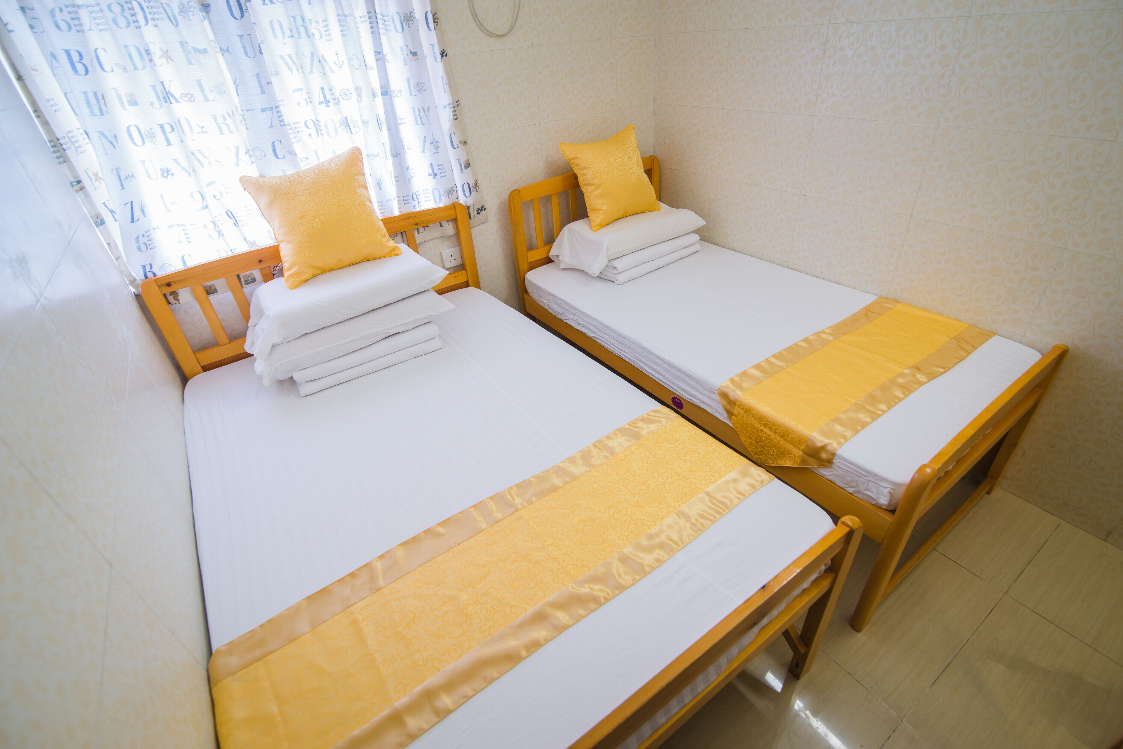 Two single beds with wooden frames, white linens, and yellow accents.
