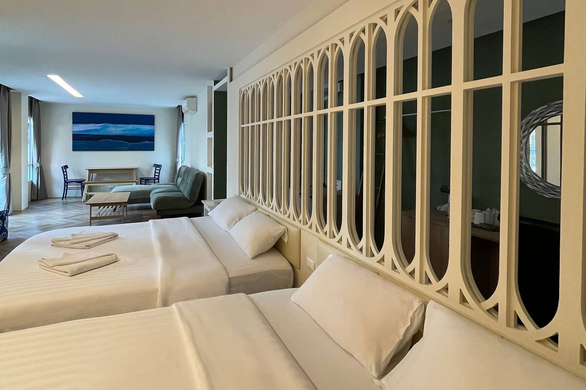 A hotel room with two beds, a seating area with a table and chairs, and a large window with a view.