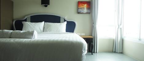 Una cama bien hecha con sábanas blancas en una habitación de hotel con vista al mar a través de una ventana.