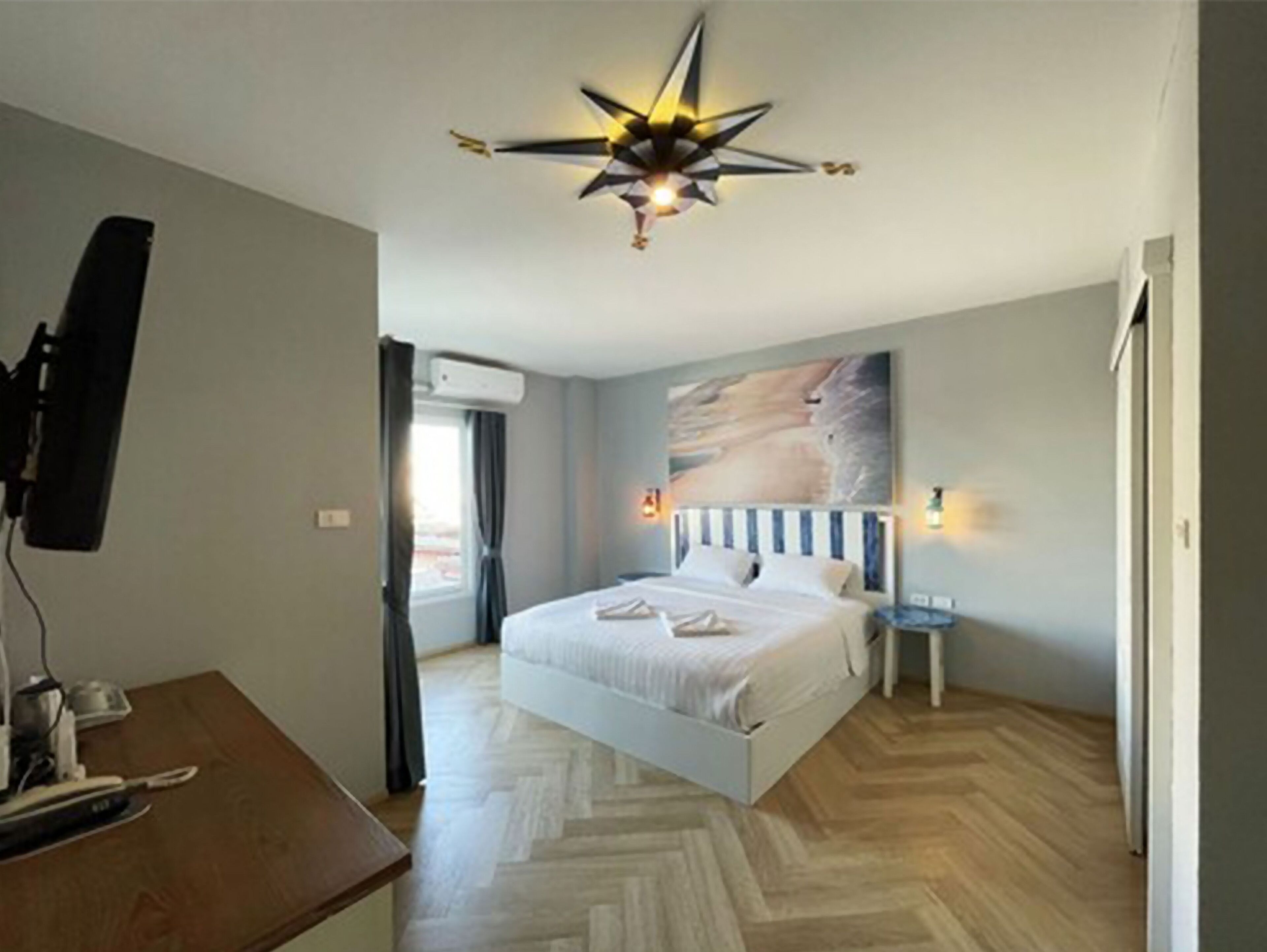 Un dormitorio con cama, escritorio, ventilador de techo y televisor de pared.