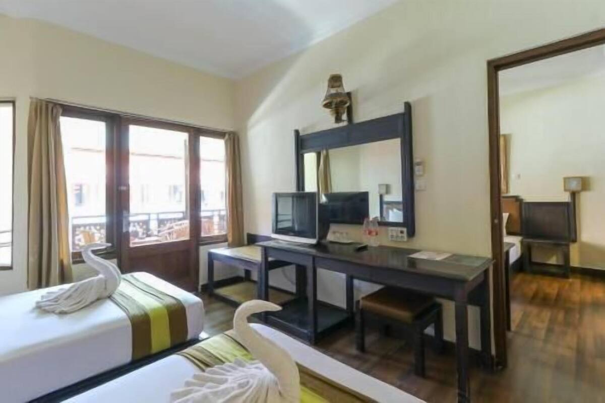 Una habitación de hotel con cama, escritorio, silla, televisor y ventana.