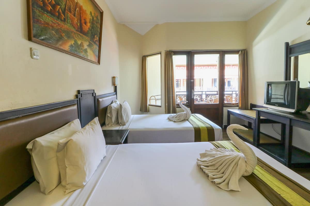 Habitación de hotel con dos camas, un televisor y un cuadro en la pared.