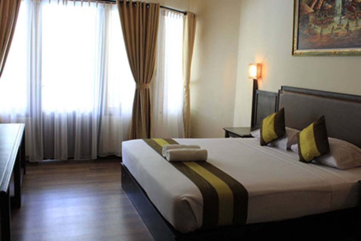 Habitación de hotel con una cama grande, una mesita de noche, una lámpara y un cuadro en la pared.