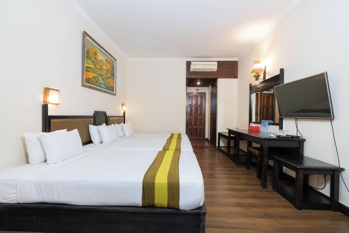 Una habitación de hotel con una cama grande, un escritorio, un televisor y un cuadro en la pared.