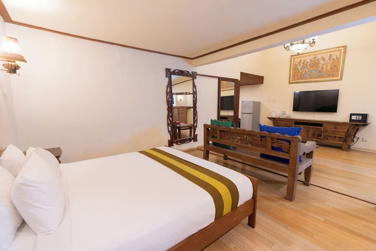 Una habitación de hotel con una cama grande, muebles de madera, un televisor y un espejo decorativo.