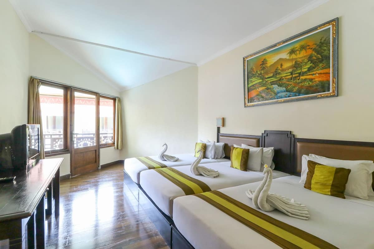 Habitación de hotel con dos camas, un cuadro en la pared, un escritorio con televisor y un balcón con cortinas.