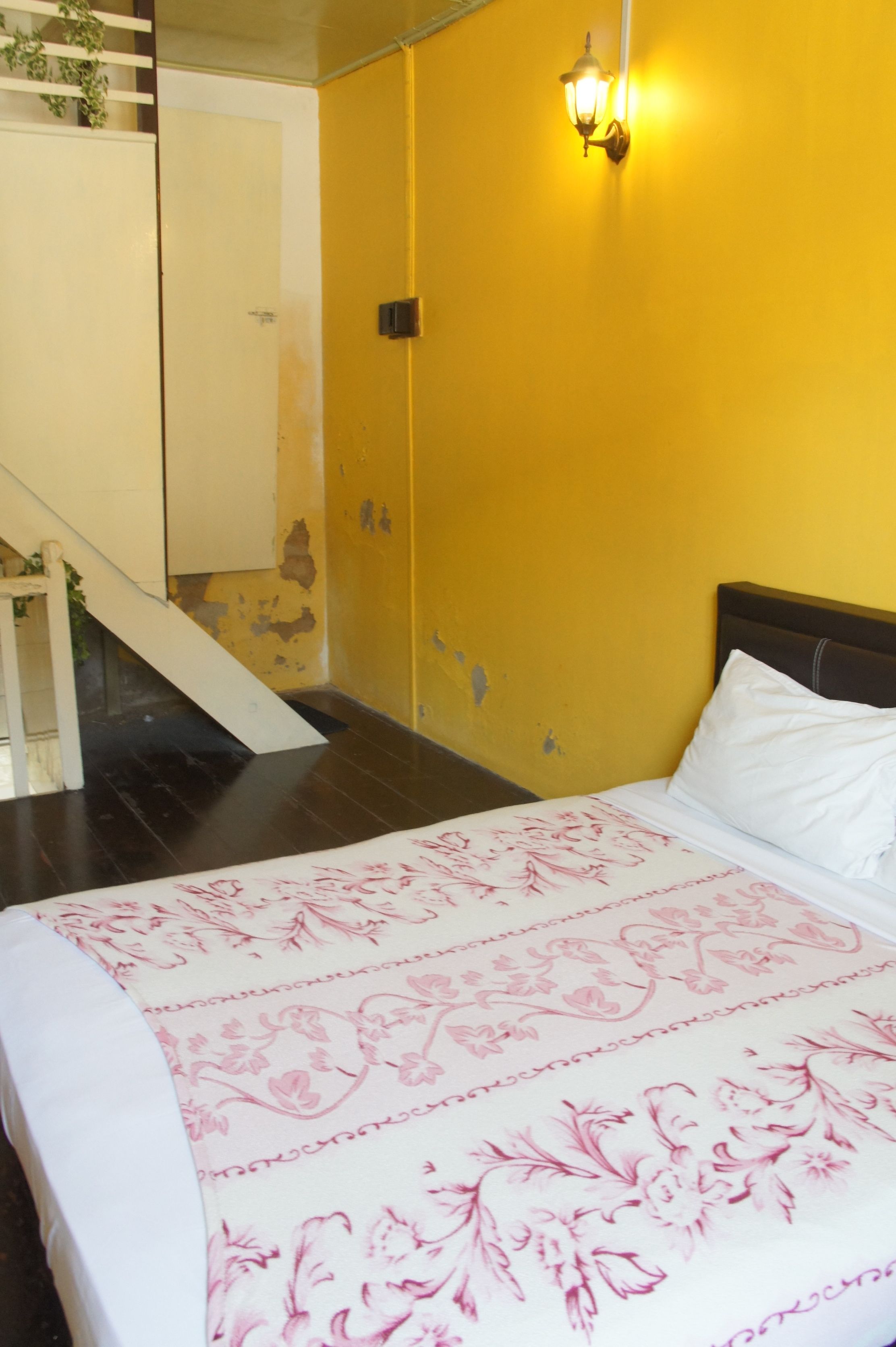 Una habitación con una cama, una escalera y una pared amarilla.