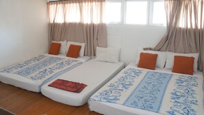 Una habitación con dos camas individuales, cada una con una colcha estampada y almohadas naranjas.