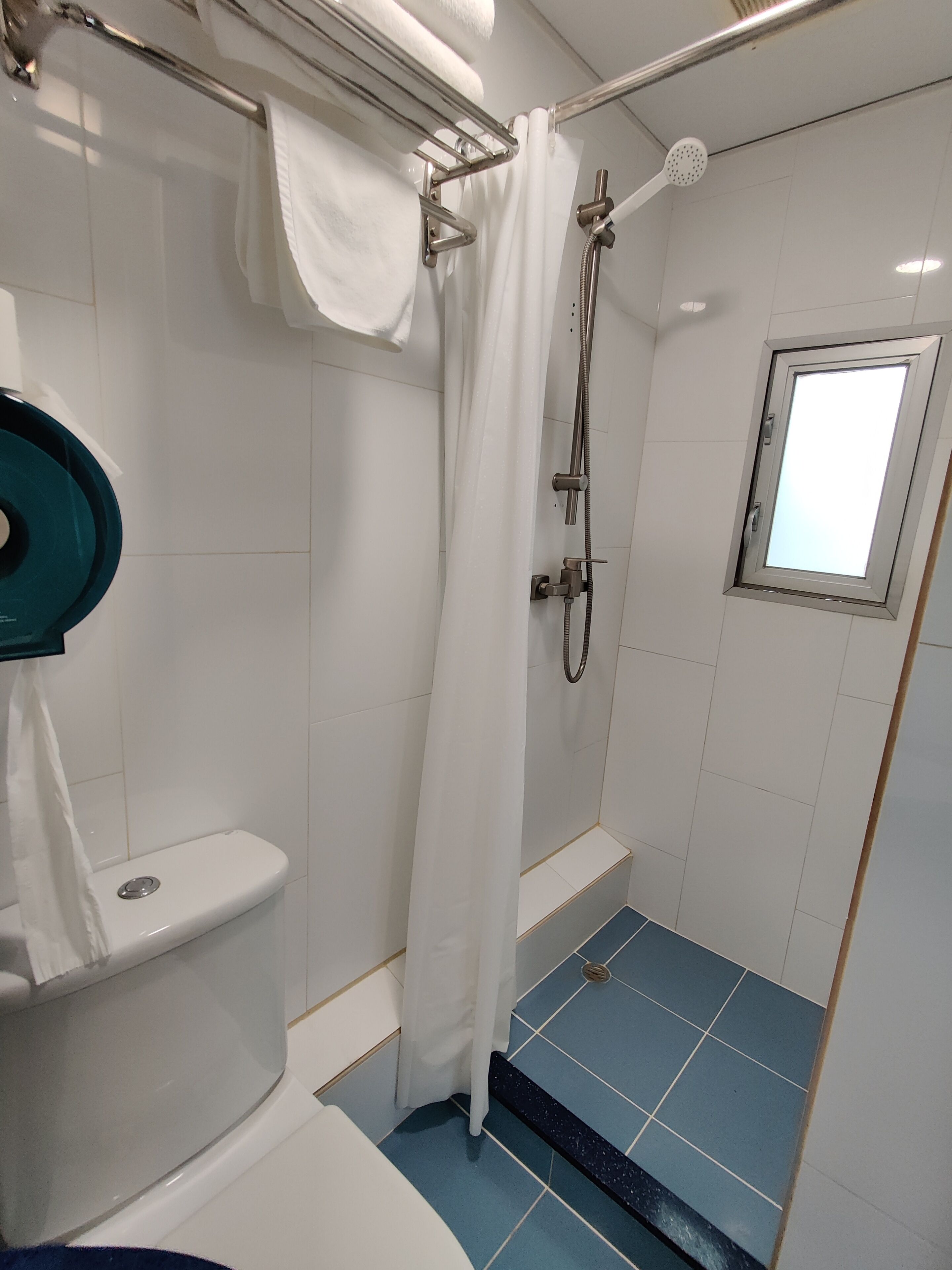 Un baño con ducha, inodoro y ventana.