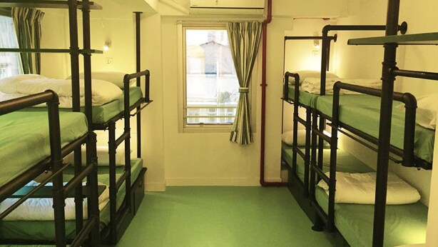 Une chambre de dortoir avec des lits superposés, une fenêtre avec des rideaux et un radiateur.