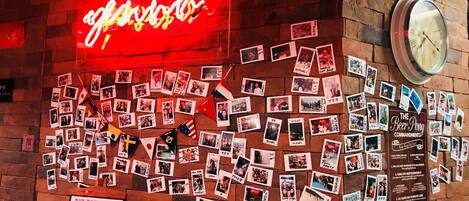 Una pared con un letrero de neón, fotografías y un reloj.