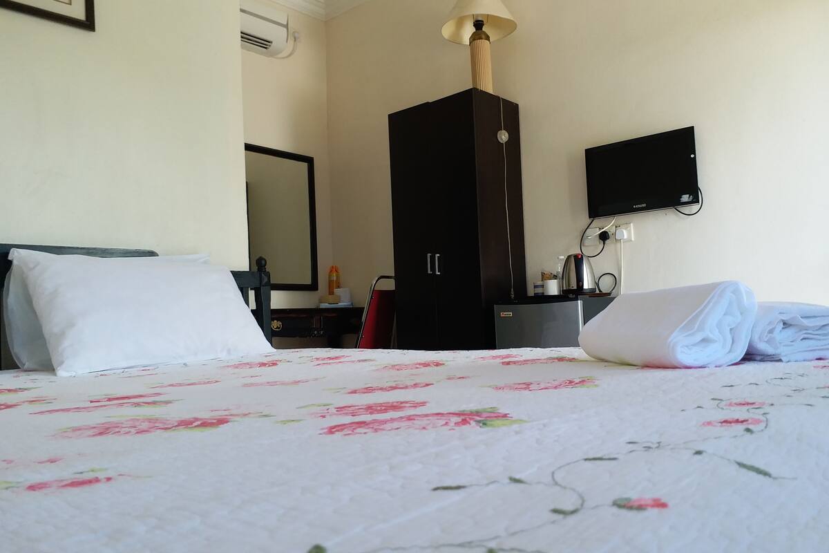 Une chambre d’hôtel équipée d’un lit, d’un bureau, d’une armoire, d’une télévision et d’une lampe.