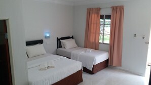 A hotel room with two beds, a window with curtains, and a light fixture on the wall. - Idaman Guesthouse (Langkawi)