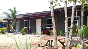 A building with a porch, a table, and chairs. - Idaman Guesthouse (Langkawi)