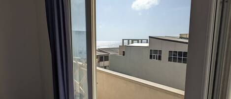 A balcony with a view of the sea and buildings.