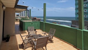 A balcony with a view of the ocean, wooden chairs, and a small table. - Palmyrah Residencies (Colombo)