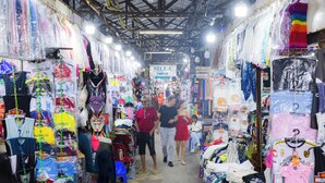 Un mercado interior animado con varios puestos que venden ropa y accesorios.