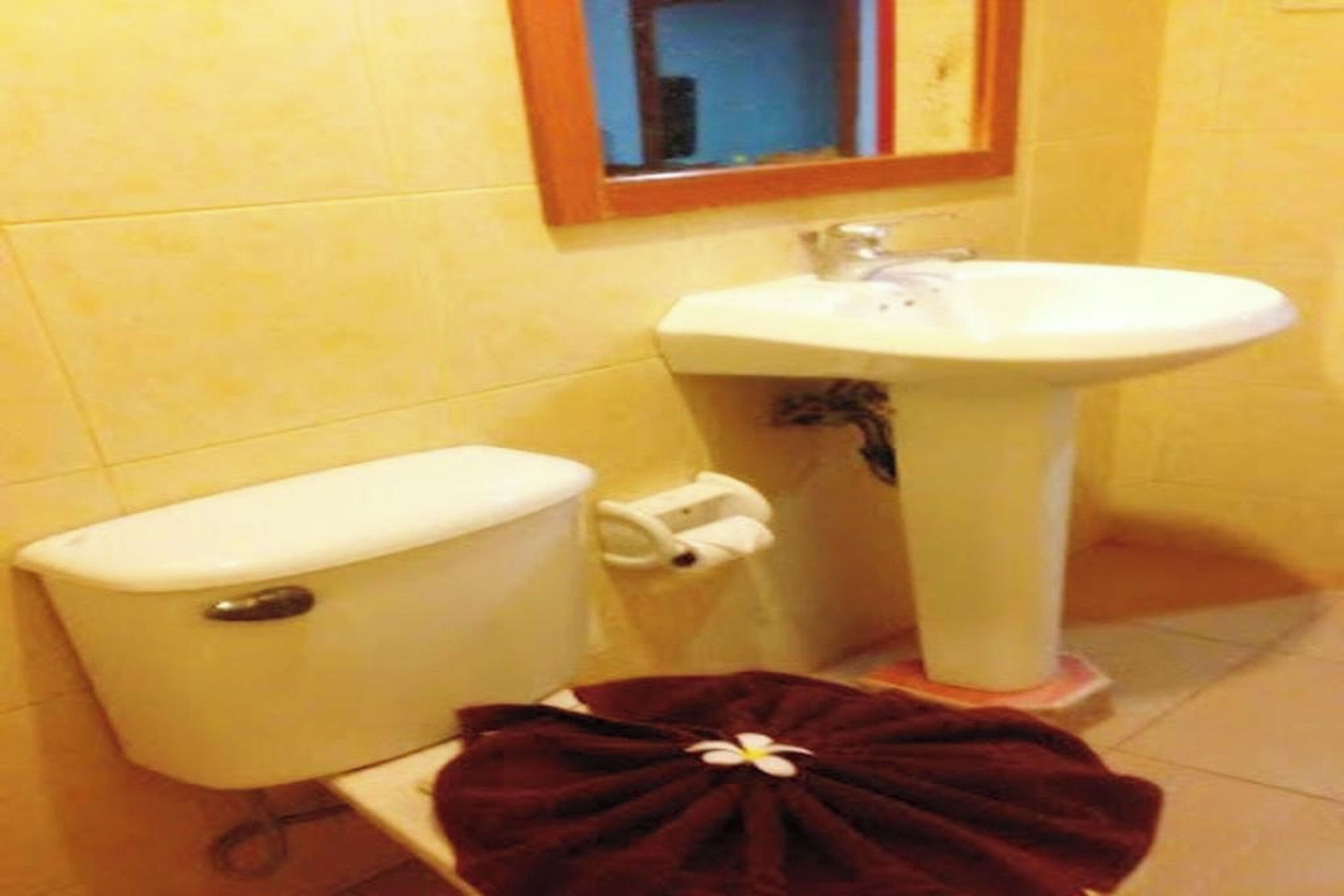 Un baño con inodoro, lavamanos y una toalla en el suelo.