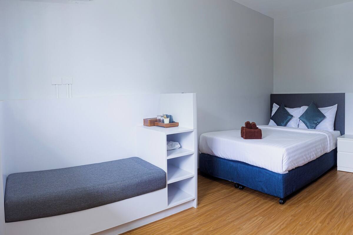 A modern bedroom with a bed, a bench, and a white wardrobe.