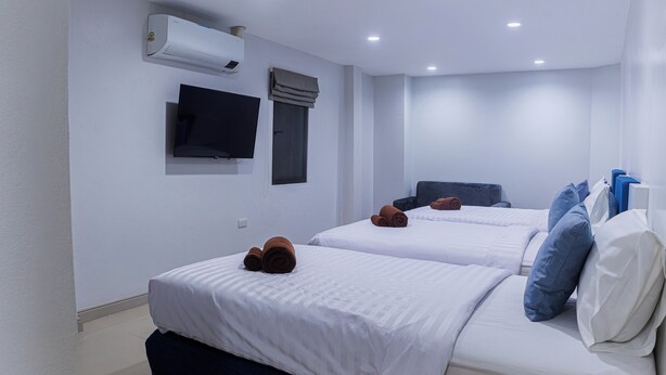 Habitación de hotel con dos camas, un televisor de pantalla plana, aire acondicionado y una ventana con cortinas.
