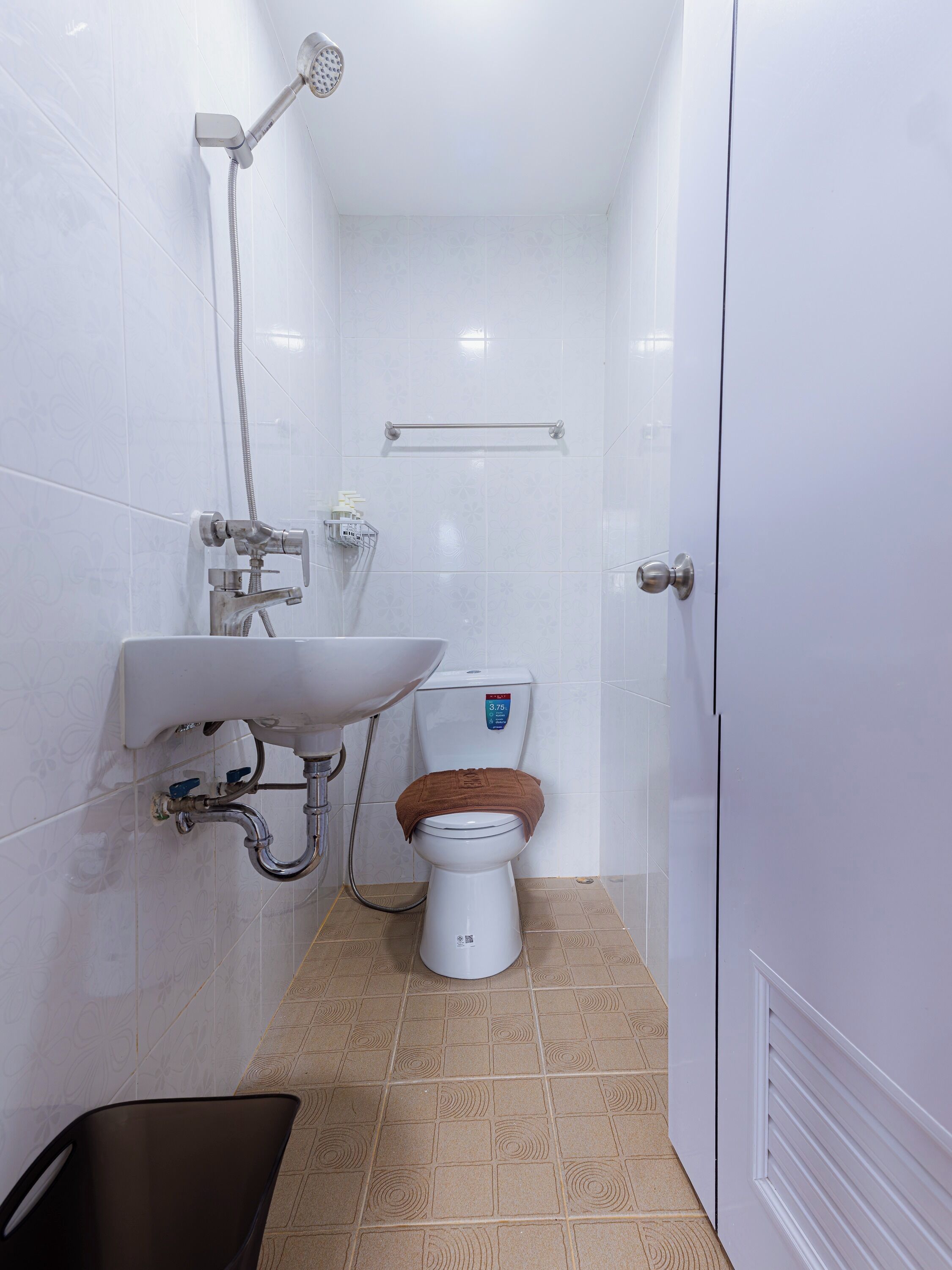 A small, white bathroom with a toilet, sink, and shower.