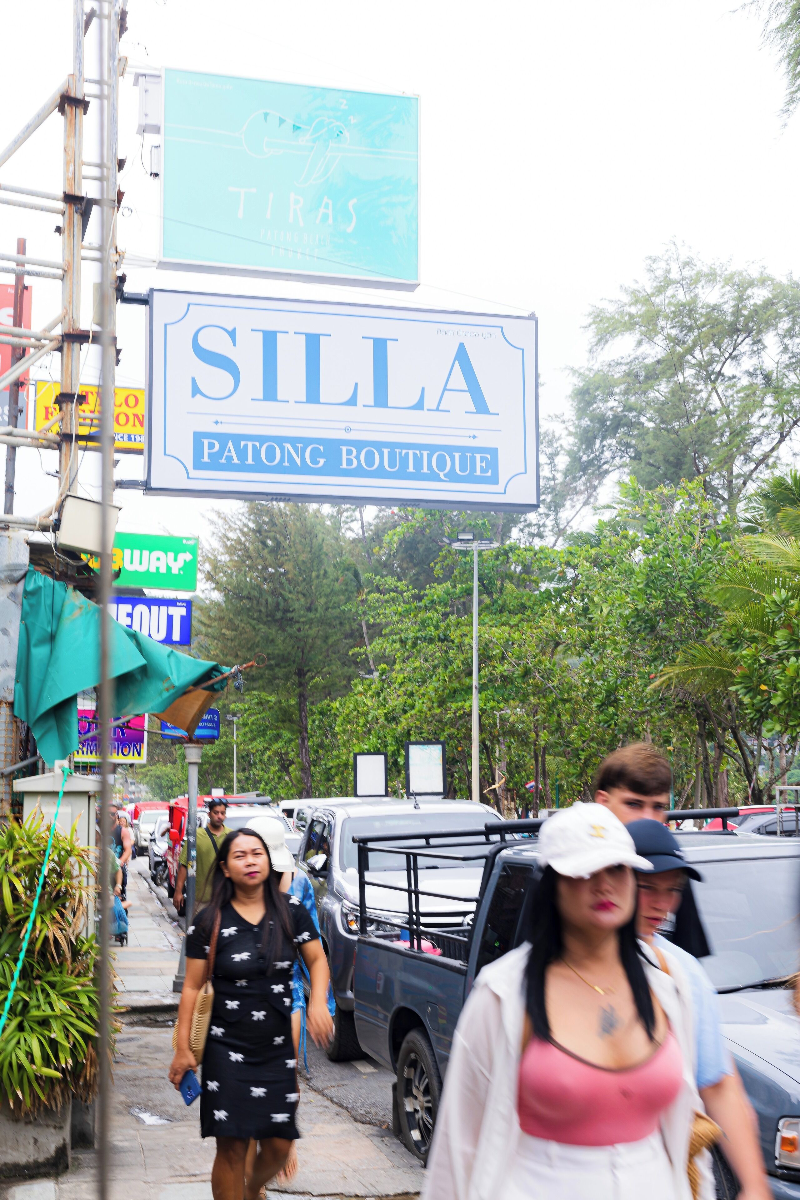 A street scene with a sign for 'SILLA PATONG BOUTIQUE' and various other signs and vehicles.