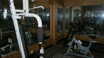 A gym with exercise equipment, mirrors, and a patterned carpet.