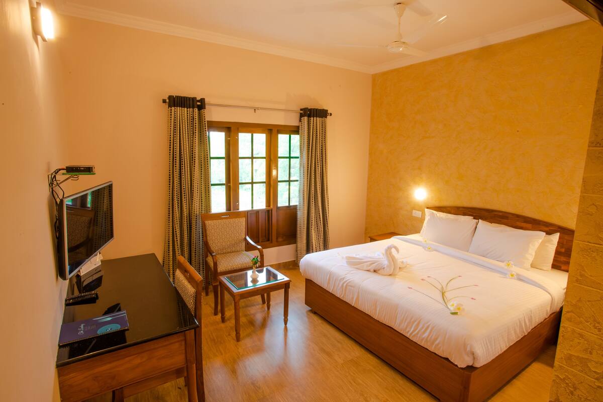 Una habitación de hotel con cama, escritorio, silla y televisor.