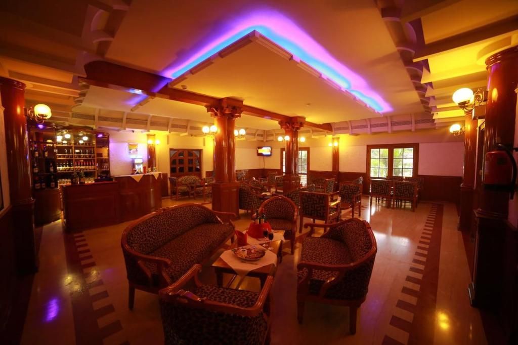 A hotel lobby with a bar area, seating arrangements, and a television screen.