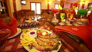 Una mesa de comedor con mariscos, diversas bebidas y un interior de restaurante acogedor.