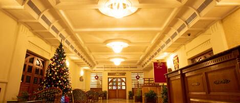 A grand lobby with a large Christmas tree, wooden furniture, and a red banner.
