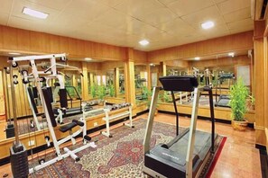 A gym with various exercise equipment, including treadmills and weight machines, and mirrors on the walls. - Quality Airport Hotel (Aluva)