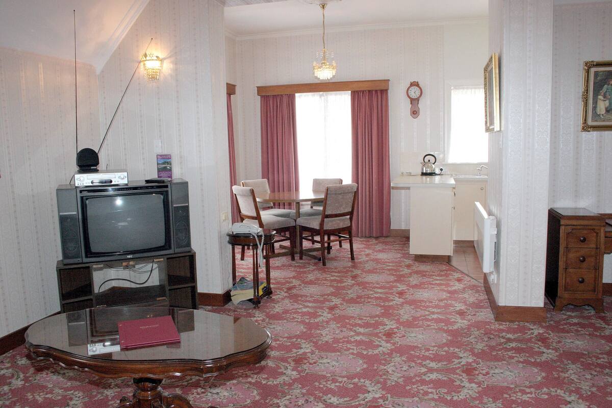 A living room with a television, a glass coffee table, and a dining area with a table and chairs.