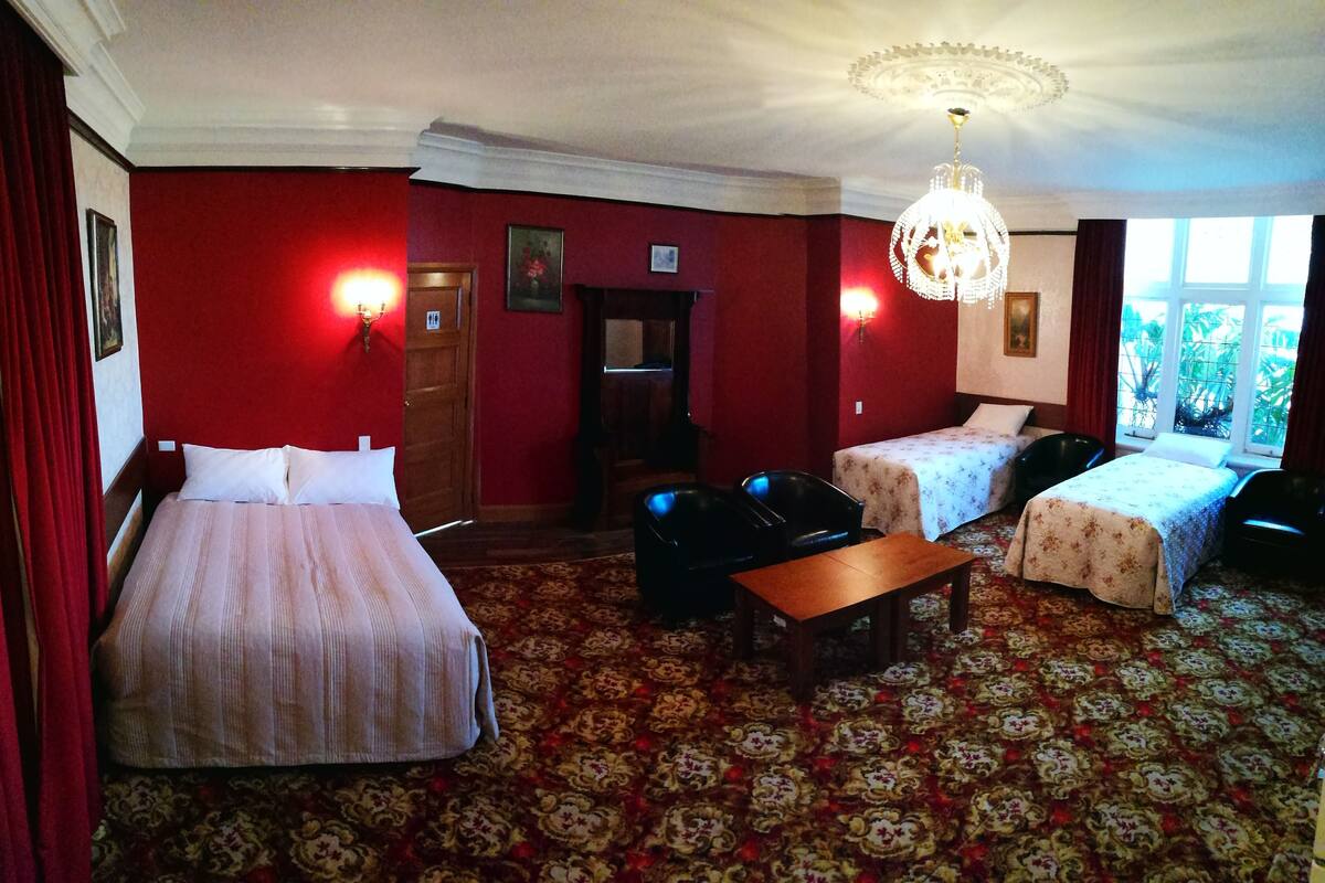 A hotel room with two beds, a wooden table, and a chandelier.
