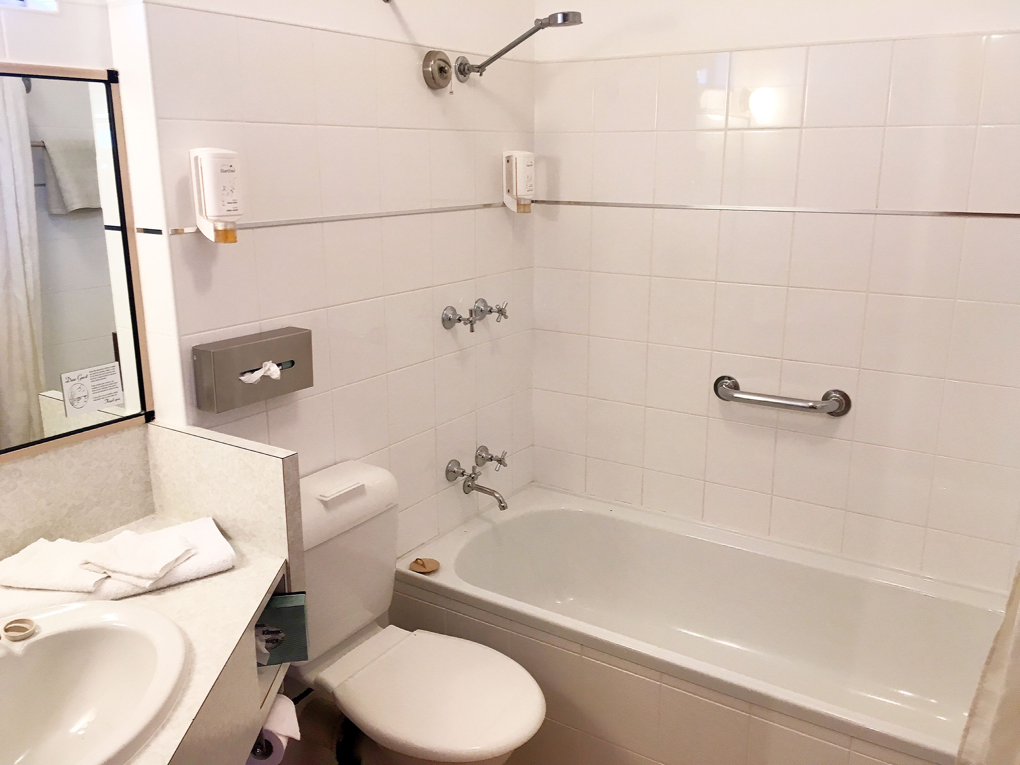 A bathroom with a bathtub, toilet, sink, and a hand dryer.