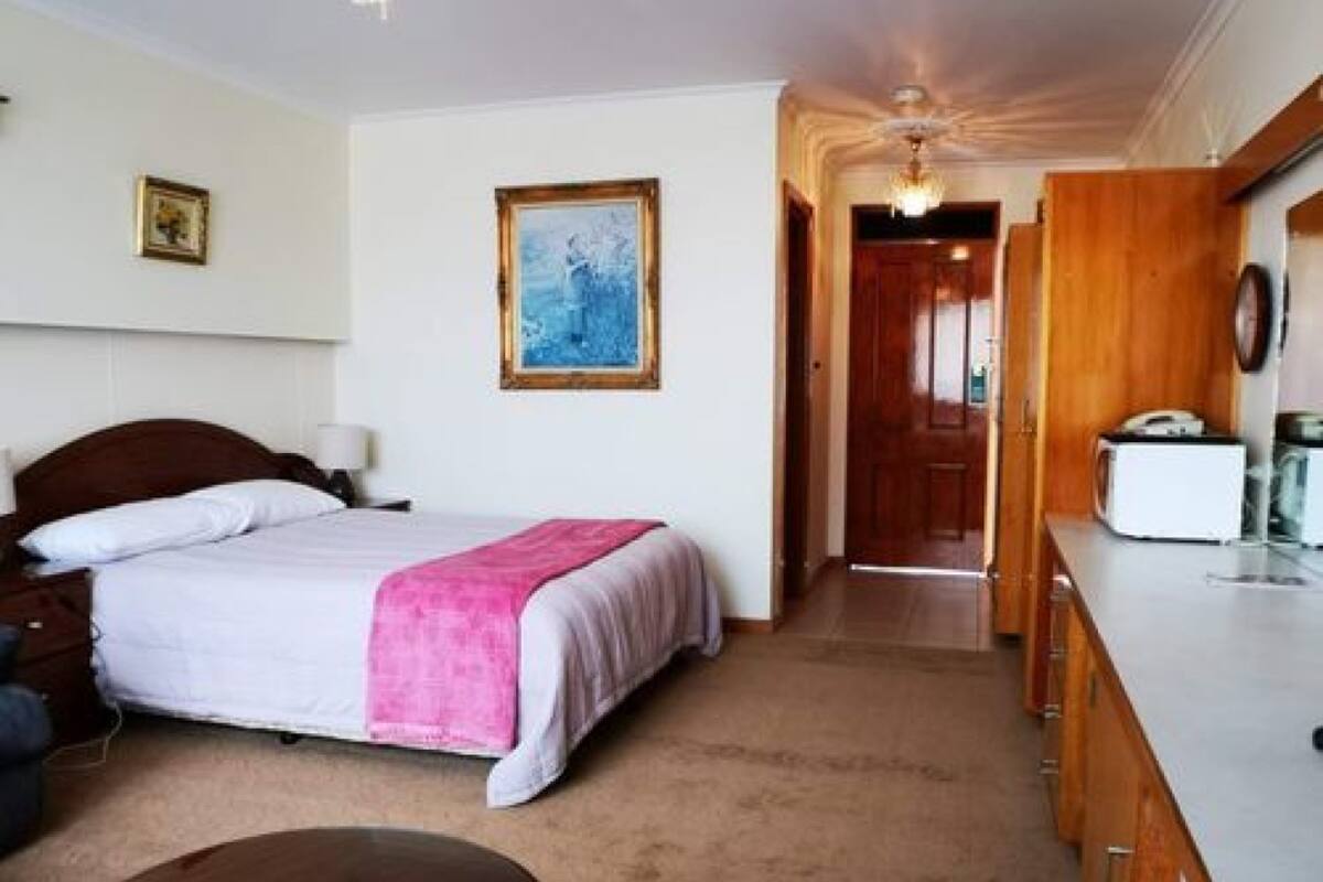 A bedroom with a bed, bedside table, and a painting on the wall.