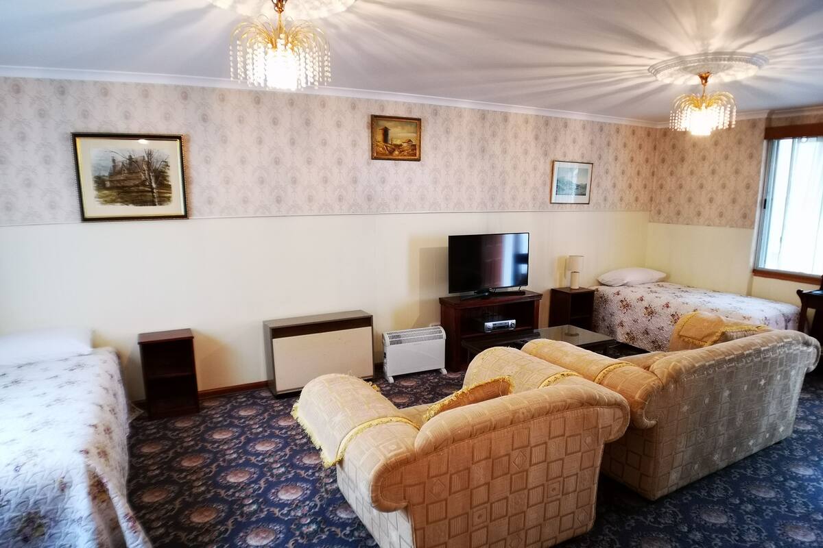 A hotel room with a sofa set, a TV, a small table, and a bed.