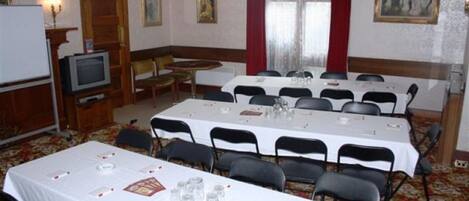 A conference room with multiple tables and chairs, a television, and framed artwork on the walls.