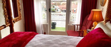 A hotel room with a bed, a chair, a lamp, a mirror, and a view of the outside.