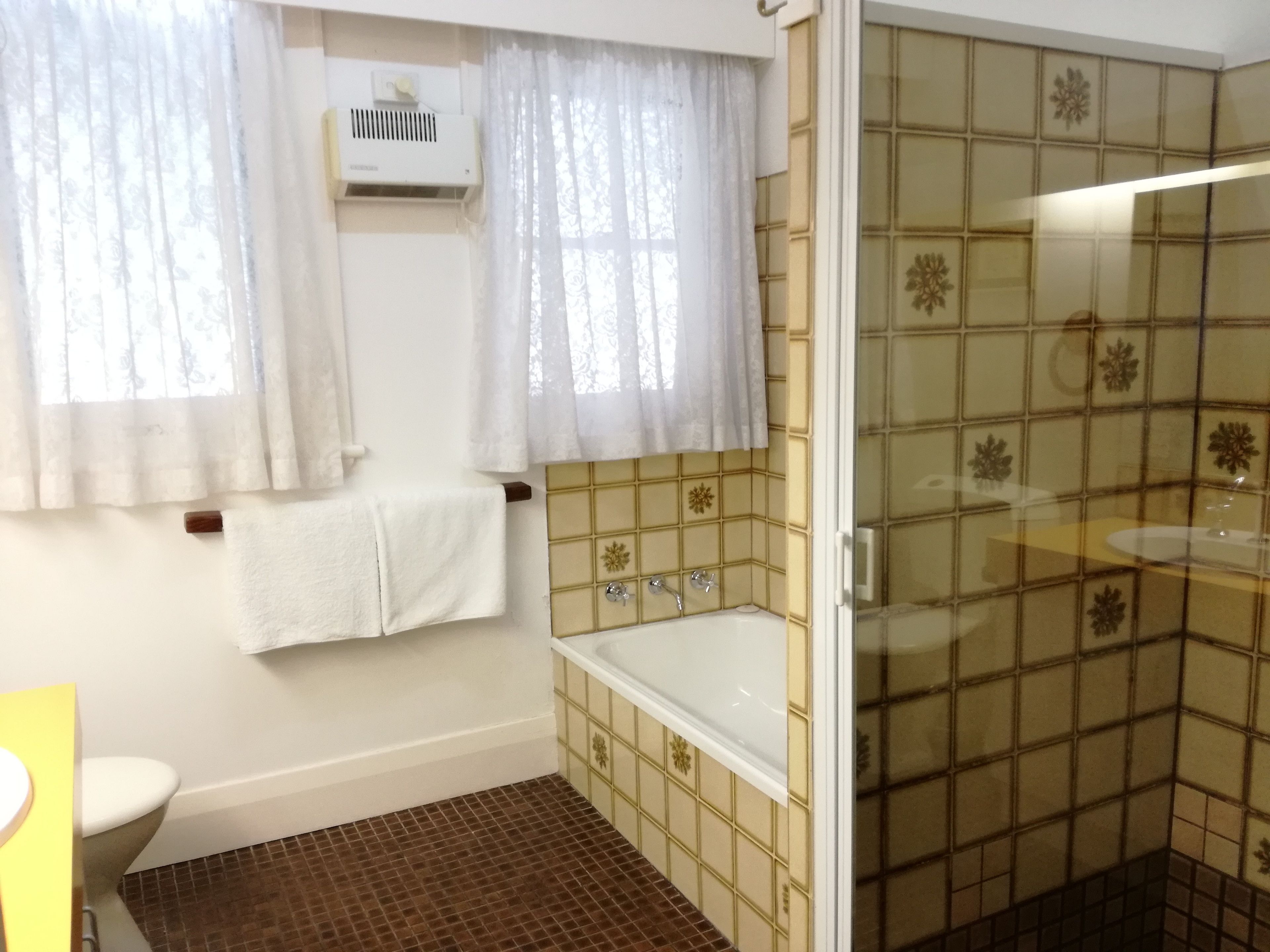 Baño con bañera, inodoro y ventana con cortinas.