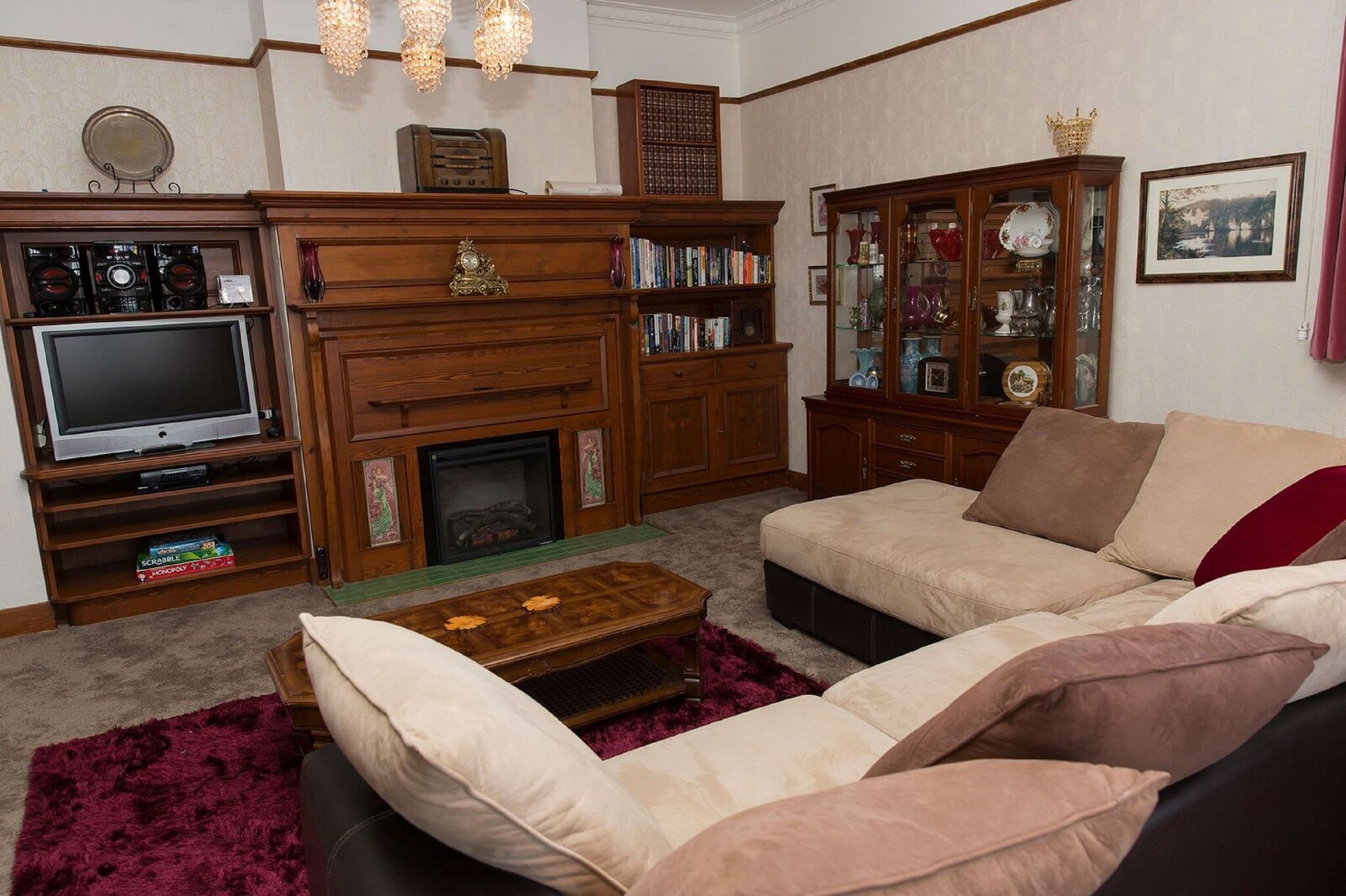 Una sala de estar con chimenea, televisor, estantería y sofá.