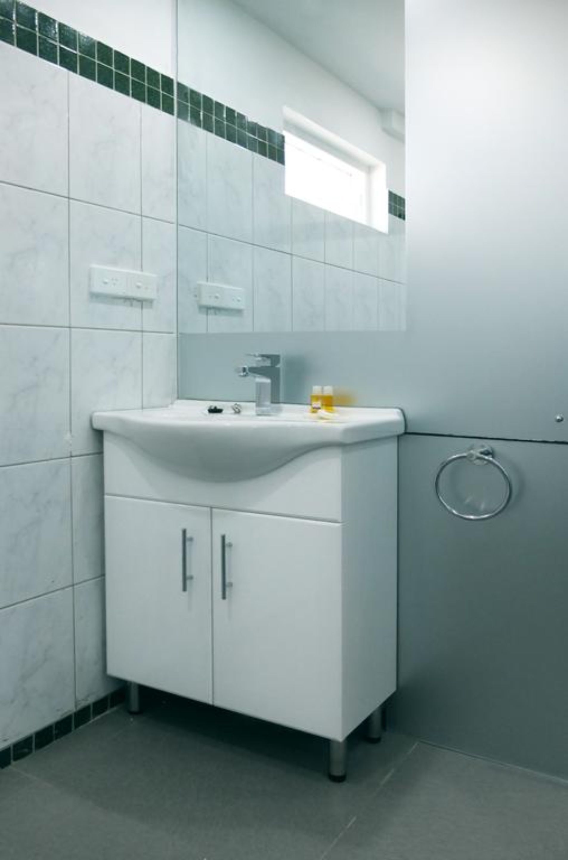 A bathroom with a white sink, mirror, and cabinet.
