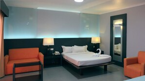 A hotel room with a bed, two nightstands, two lamps, a mirror, and two orange chairs. - Southern Cross Hotel Fiji (Suva)