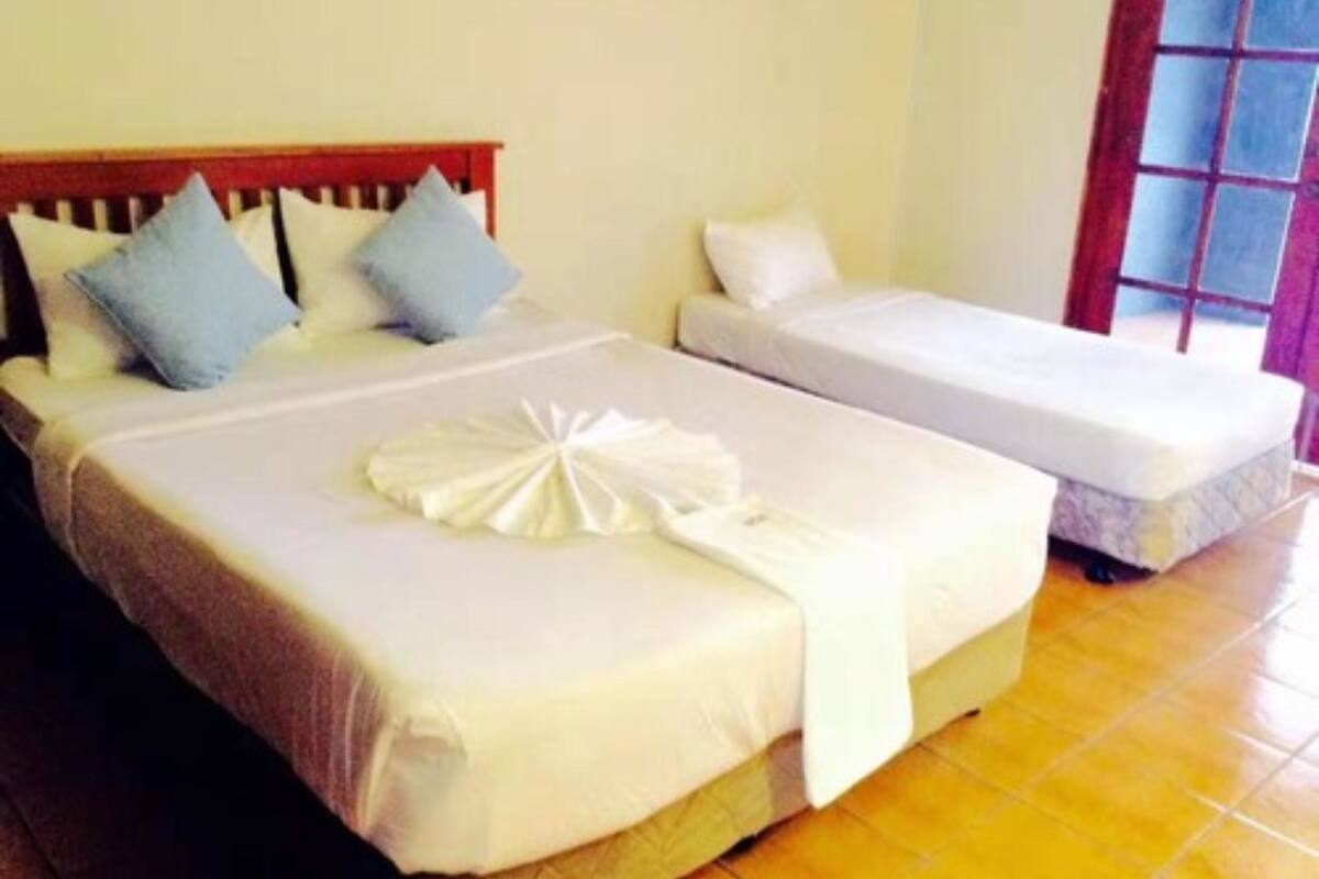 A hotel room with two beds, one larger and one smaller, both with white linens.