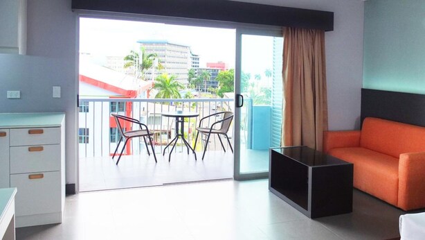 A modern hotel room with a balcony, a sofa, a desk, and a dining area. - Southern Cross Hotel Fiji (Suva)