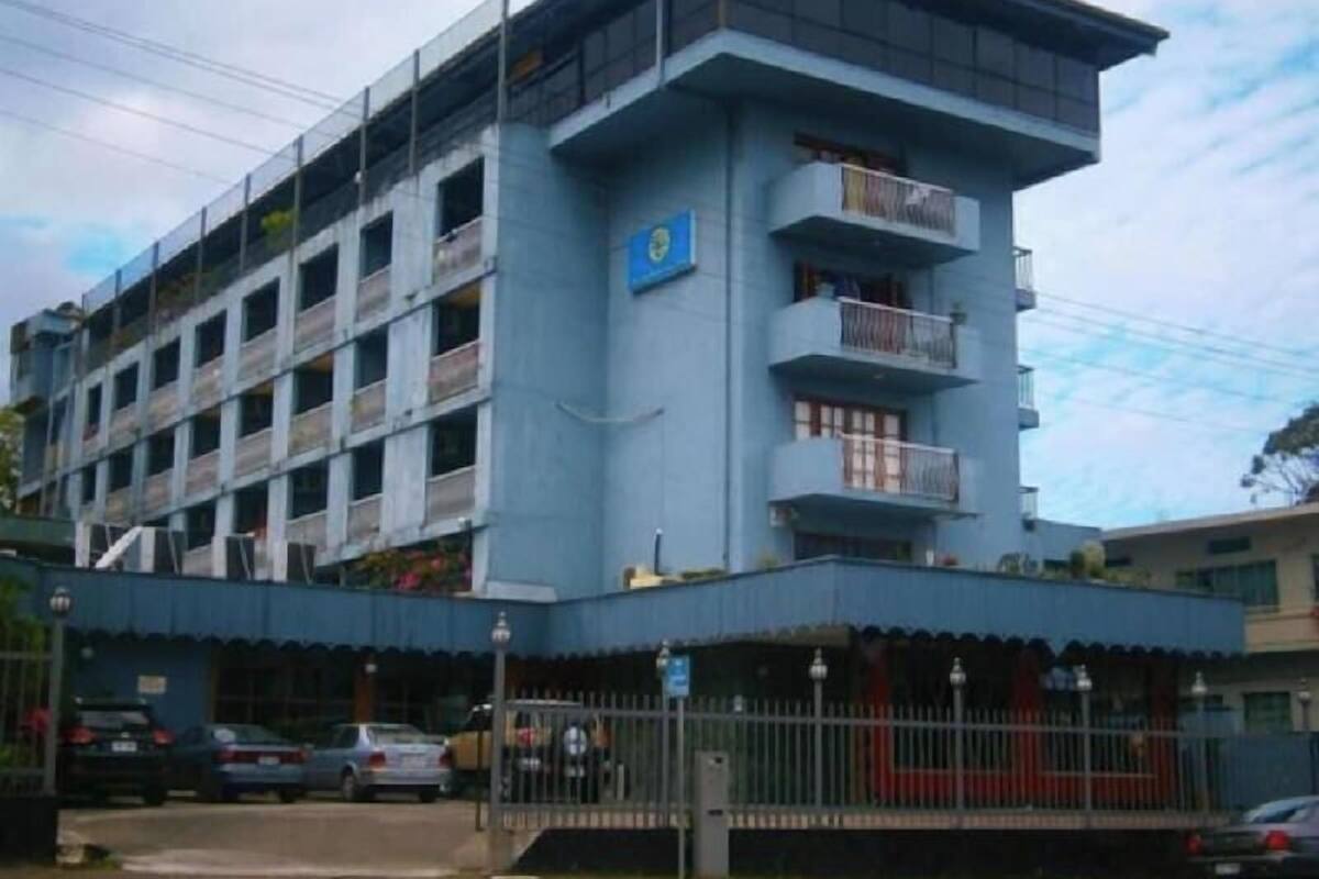 A multi-story building with balconies, a blue sign, and a gated entrance.