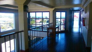 A hallway with large windows, wooden flooring, and a staircase. - Southern Cross Hotel Fiji (Suva)